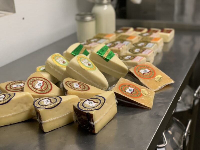 Variety of Vella Cheeses spread out on a stainless steel table inside the Moreda Family Farms creamery
